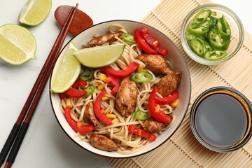 Delicious noodles with meat and vegetables served on white marble table, flat lay