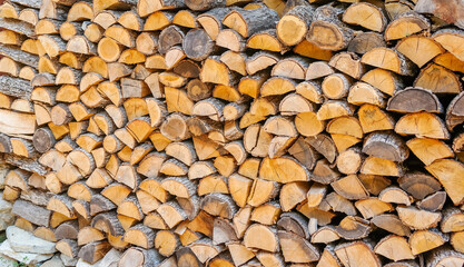 Stacked firewood near the house. Preparation of firewood for winter, chopped bundles of firewood, warmth by the fireplace