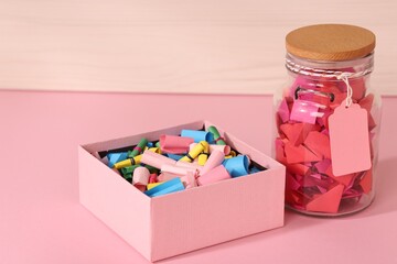 Color paper pieces in box and glass jar on pink table