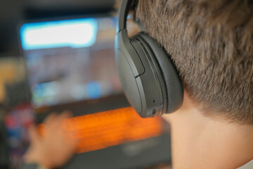 Boy with headphones playing video games on laptop at home