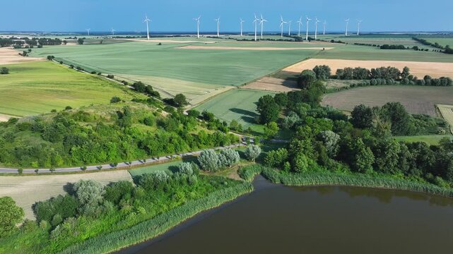 Aerial view of lush green fields meet modern wind turbines, creating a striking contrast between nature and technology, Br&uuml;ssow Uckermark, Brandenburg, Germany.