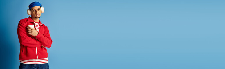 Stylish young man in a beanie hat radiates confidence against a blue backdrop