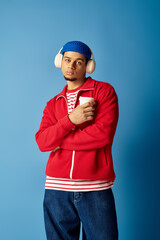 Trendy young man sipping coffee against a vibrant blue background