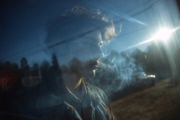 A young man is quietly smoking while gazing outside through a window, soft morning light illuminating his features Generative AI
