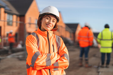 Portrait of Young female Construction works superviser overseeing building site activities  during sunny day while holding project files and wearing safety gear