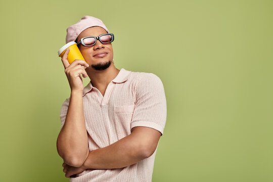 Sophisticated young man in pink attire exudes style against vibrant green backdrop