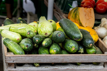 Wooden crate with assorted zucchinis and squashes, vegetables nearby