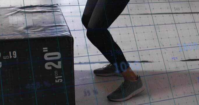 Fototapeta Bending legs in black leggings in gym, with labeled plyo box and grid overlay, copy space