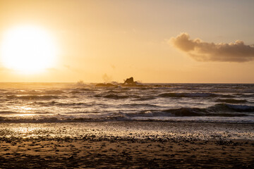 Rock in the sea whipped by waves at sunset