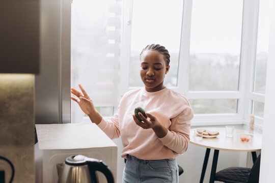 Woman choosing avocado for breakfast in modern kitchen