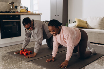 Two black women doing push-ups together at home