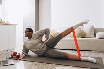 Woman performing leg exercises with resistance band at home