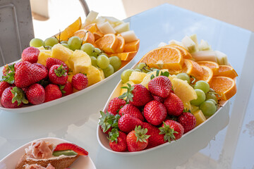 Fresh and colorful fruit platter featuring strawberries, oranges, melons, and grapes, served at a vibrant party, showcasing healthy snacks full of vitamins and delicious flavors