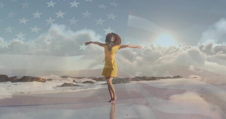 Naklejka premium Dancing barefoot woman in yellow dress twirling on wet sand beach, with faint American flag overlay