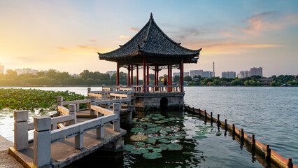 Traditional Chinese pavilion by the lake at sunset