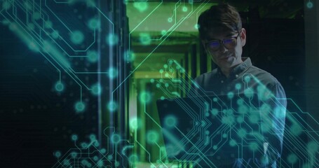 Standing technician wearing shirt holding laptop in server corridor with racks, cables, copy space