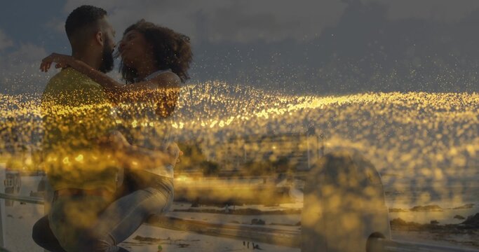 Kissing romantic couple on metal railing at sandy beach and ocean waves, golden light scattering - Powered by Adobe