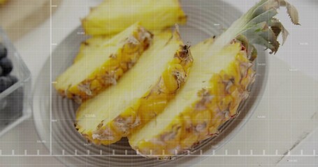Displaying fresh pineapple slices on grey plate on wooden table, with blueberries in container