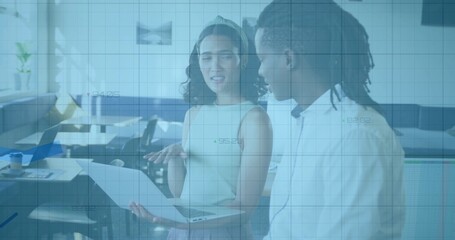 Office colleagues discussing printed document in open-plan office, with computer monitor