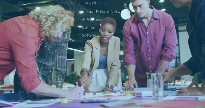 Leading woman in beige blazer, blue top pointing at diagrams on office table, with sticky notes