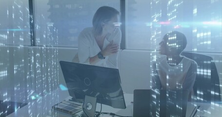 Discussing design two professional women leaning on desk using monitor at office, with swatch book