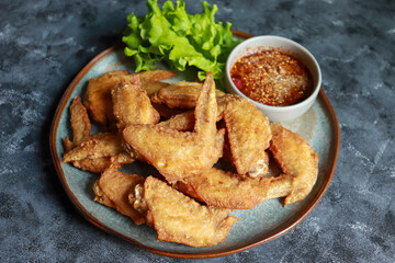 Crispy Fried Chicken wings with Fish Sauce serve with spicy dipping sauce, Delicious Thai food.