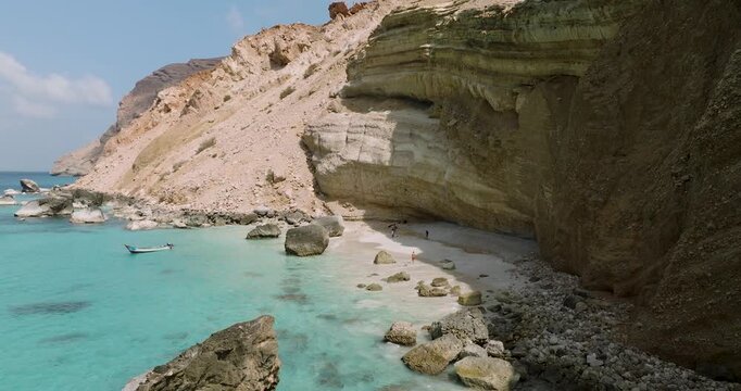 Aerial view of the turquoise waters meeting the sandy shore at Shoab Beach, contrasted against the layered cliffs, Shoab Beach, Socotra, Yemen.