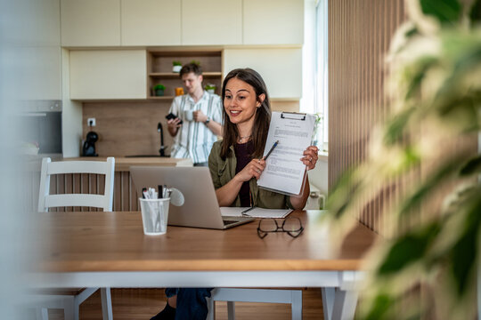 Woman showing document during video call in home office