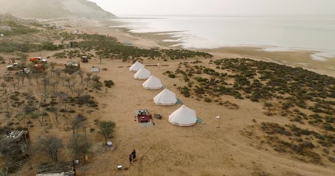 Aerial view of white tents positioned along the sandy coastline near Detwah Lagoon, creating a striking contrast against the arid landscape, Detwah lagoon, Socotra, Yemen.