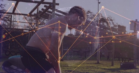 Pausing adult male catching breath at outdoor calisthenics park, with wooden monkey bars