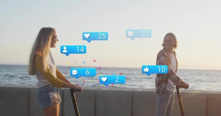 Riding couple facing on electric scooters on seawall at sunset, with floating media reaction icons