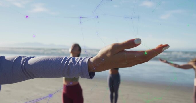 Extending lavender-sleeved arm during team yoga practice on beach, with digital overlay, copy space