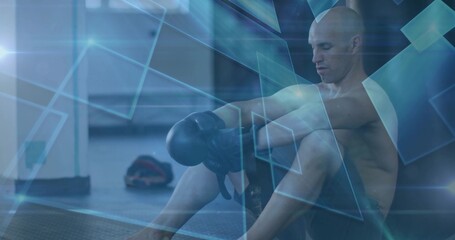 Adjusting boxing gloves athlete wearing black shorts on gym mat with geometric overlay, copy space