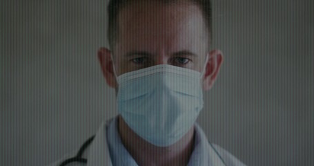 Posing adult doctor wearing light blue surgical mask and white lab coat with stethoscope in clinic
