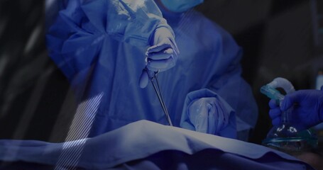 Performing surgeon using forceps on draped incision in OR, with anesthesia mask and lights
