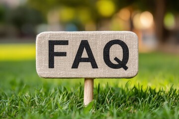 A fabric sign displaying "FAQ" is placed in a green grassy area, suggesting a focus on frequently asked questions in a natural setting.