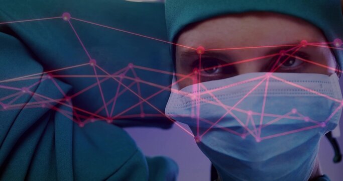 Surgeon in green scrubs, cap adjusting blue glove, mask in operating room with pink network overlay - Powered by Adobe