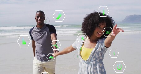 Naklejka premium Running couple holding hands along wet sand at beach shoreline, with hexagonal graphic overlays