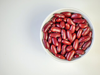 Red bean seeds in a white bowl on a white background