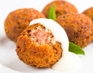 Crispy Golden Salmon Croquette with a Creamy White Sauce Broken to Reveal a Tender Pink Interior.