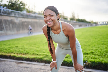 Young athletic woman taking a well-deserved break after an intense workout, smiling brightly while...