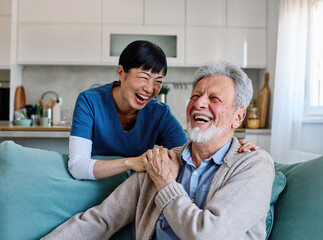 Doctor or nurse caregiver with senior man talking and having fun at home or nursing home