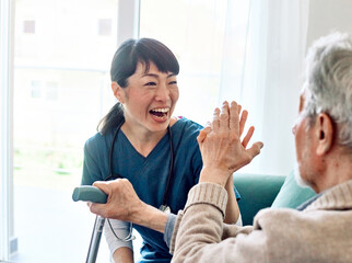 Portrait of a doctor or nurse caregiver supporting senior man, holding hands, high five gesture, at home or nursing home