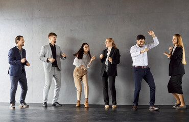 Joyful enthusiastic business team dance against grey wall, celebrate successful deal, have fun together, satisfied after nice work, glad weekends are coming. Business success concept