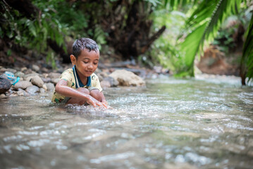 Fototapeta premium Asian boy is playing in the river