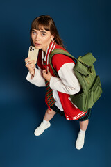 Obraz premium Young female student showcasing her stylish outfit while checking her phone in a vibrant setting