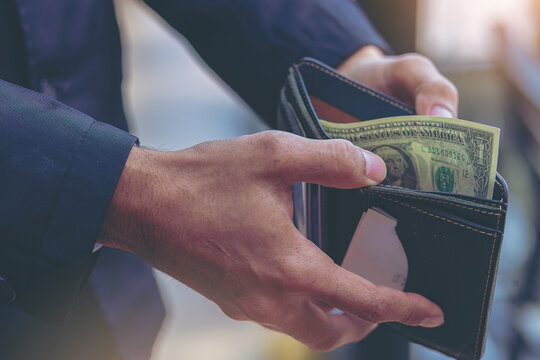 Businessman open leather wallet with a one Dollar banknote inside. Poverty, bankruptcy, and poor concept