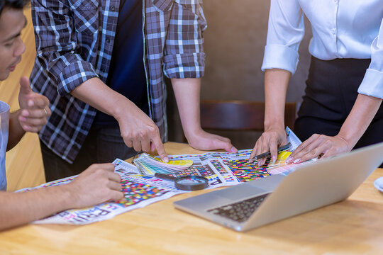 Team graphic designer checking print quality of media graphics proof print and color guides in printing industry. Selected focus