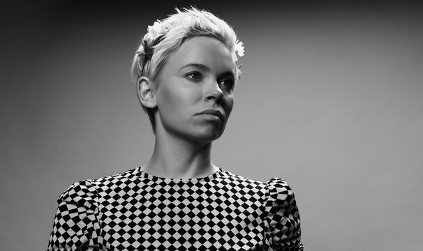 Black and white portrait of attractive blond-haired Caucasian woman in checked  blouse looking aside thoughtfully