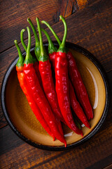 Spicy Organic red hot chili peppers in a bowl, wooden background, top view vertical photo